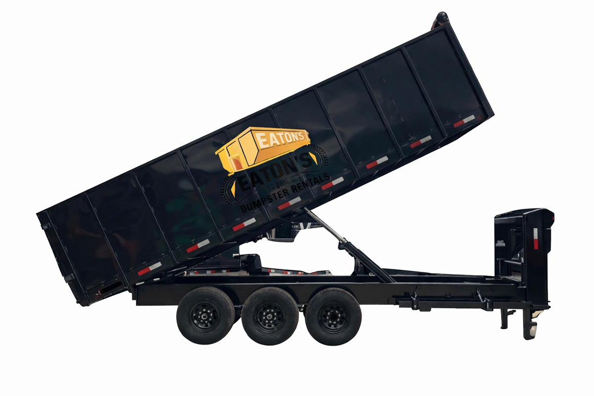 Eaton’s Dumpster Rentals black roll-off trailer raised for unloading, heavy-duty dumpster container isolated on white background for construction and renovation projects.