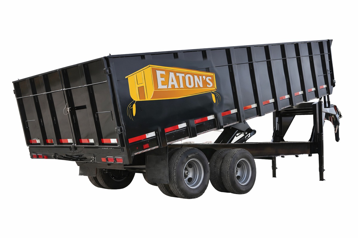 Eaton’s Construction roll-off dumpster trailer raised for unloading, black heavy-duty container isolated on white background for construction and renovation waste removal.