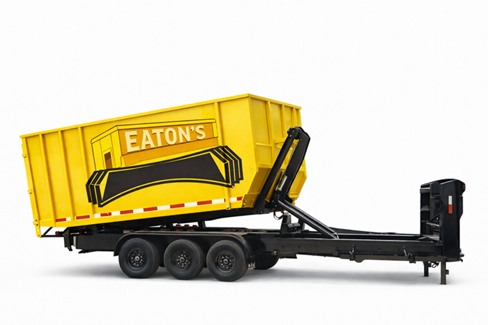 Yellow Eaton’s roll-off dumpster trailer mounted on a black triple-axle frame, isolated on a white background.